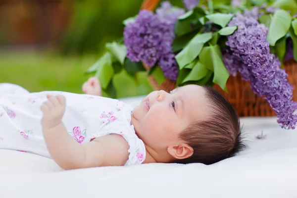 Baby girl with lilac bouquet in basket — Stock Photo, Image