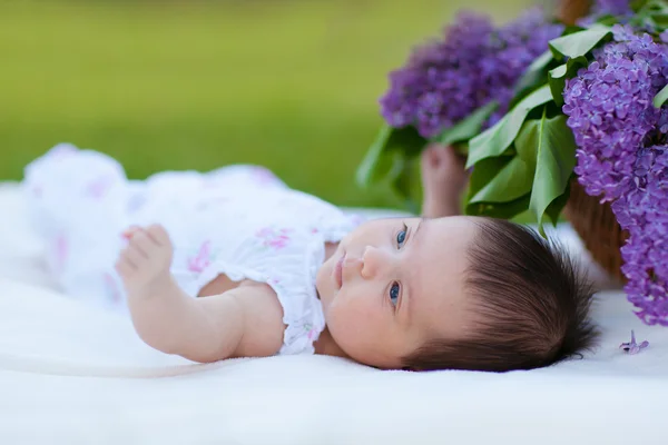バスケットのライラックの花束と女の赤ちゃん — ストック写真