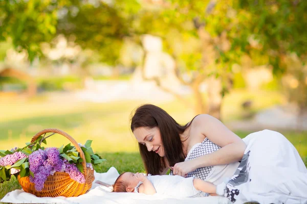 Happy mother and baby resting in summer park — Stock Photo, Image