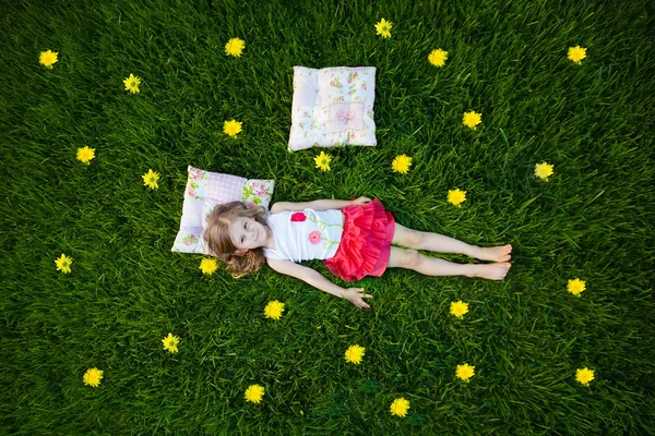 Little girl resting on pillows in summer garden — Stock Photo, Image