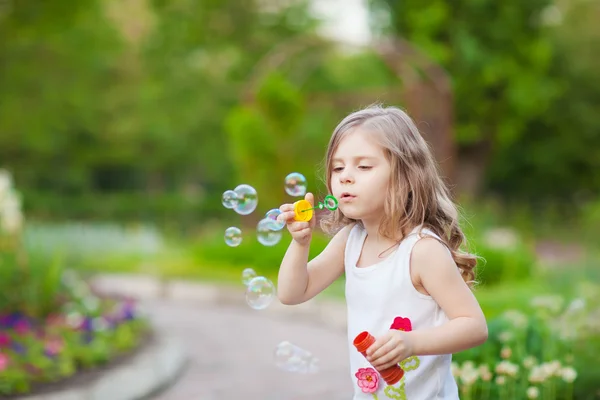 Schattig krullend meisje met zeepbellen Stockfoto