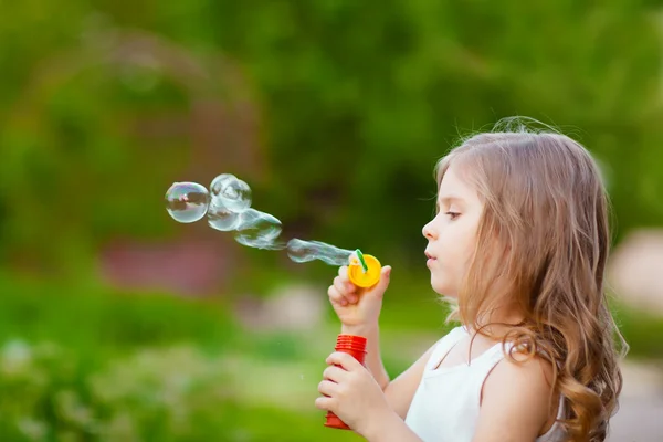 Menina encaracolado bonito com bolhas de sabão — Fotografia de Stock