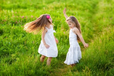 Two lovely girls playing on meadow clipart