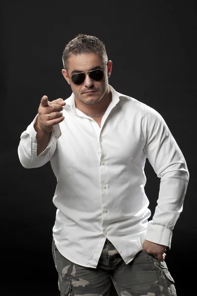 Muscular male in a white shirt standing and pointing — Stock Photo, Image