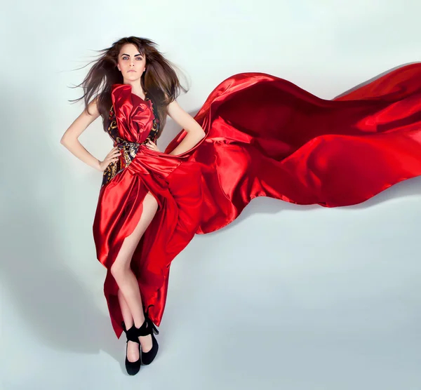 Flexibilní dívka se pohybuje v červené dlouhé šaty — Stock fotografie