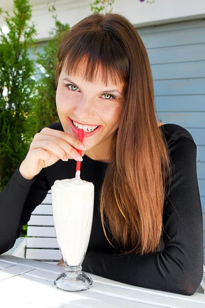 Красивая девушка пьет молочный коктейль с соломинкой — стоковое фото