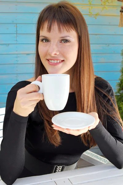 Meisje houdt een kopje van drank en glimlachte aangenaam — Stockfoto