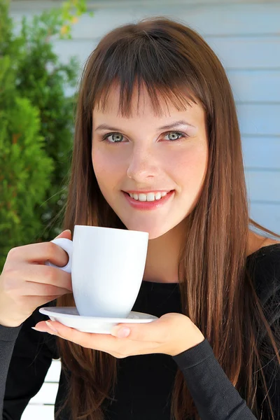 Κορίτσι, κρατώντας ένα φλιτζάνι τσάι και χαμογέλασε ευχάριστα — Φωτογραφία Αρχείου