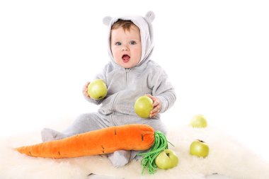 Child is sitting and holding two apples and wonders clipart