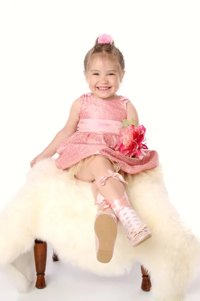Fille en robe rose assise sur une chaise de fourrure — Photo