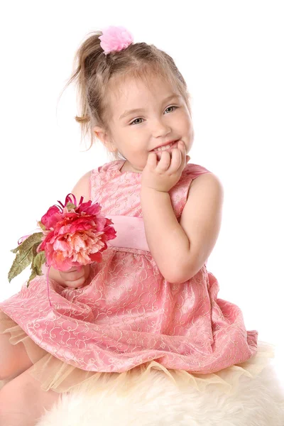 Menina em um vestido rosa com flor pensa — Fotografia de Stock