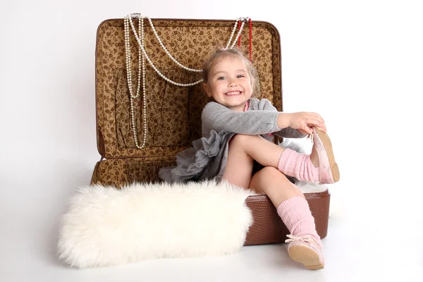 Lány ül egy bőrönd, a medve bőrén — Stock Fotó