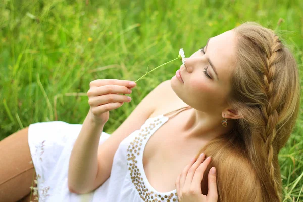 Mädchen liegt mit Kamille im Gras — Stockfoto