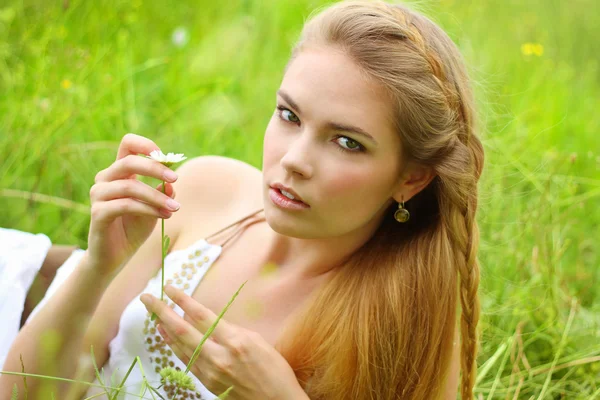 Ragazza sdraiata nell'erba con camomilla — Foto Stock