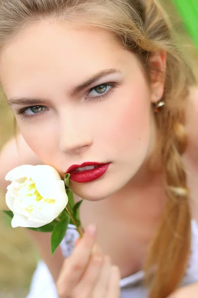 Schönes Mädchen in einem weißen Kleid mit einer Blume in der Hand — Stockfoto