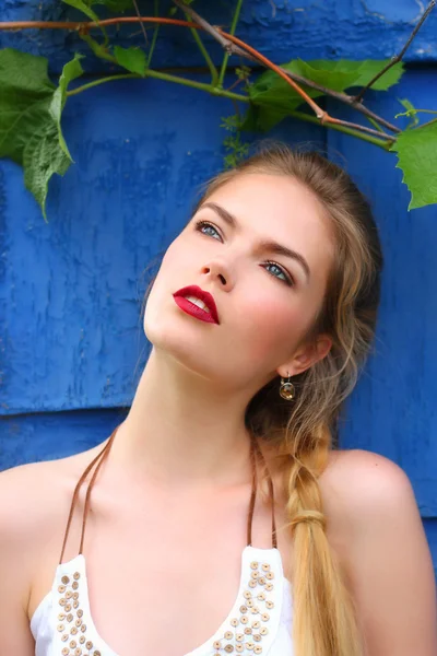 Meisje met rode lippen tegen de muur met wijnstokken — Stockfoto