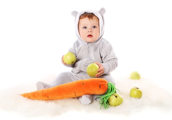 Barnet sitter och håller två äpplen och underverk Stockbild
