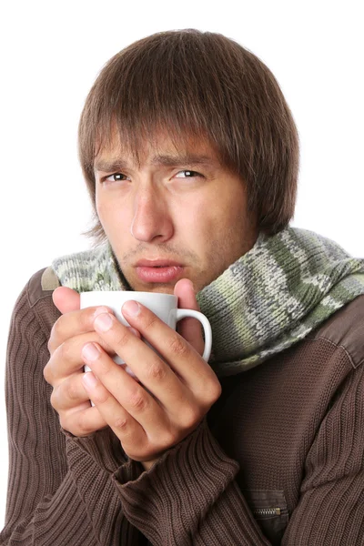 Jeune homme malade avec une température élevée réchauffe ses mains sur une tasse — Photo
