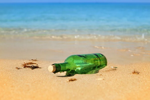 Zelená skleněná láhev s dopisem vyhodit na písečné pláži — Stock fotografie
