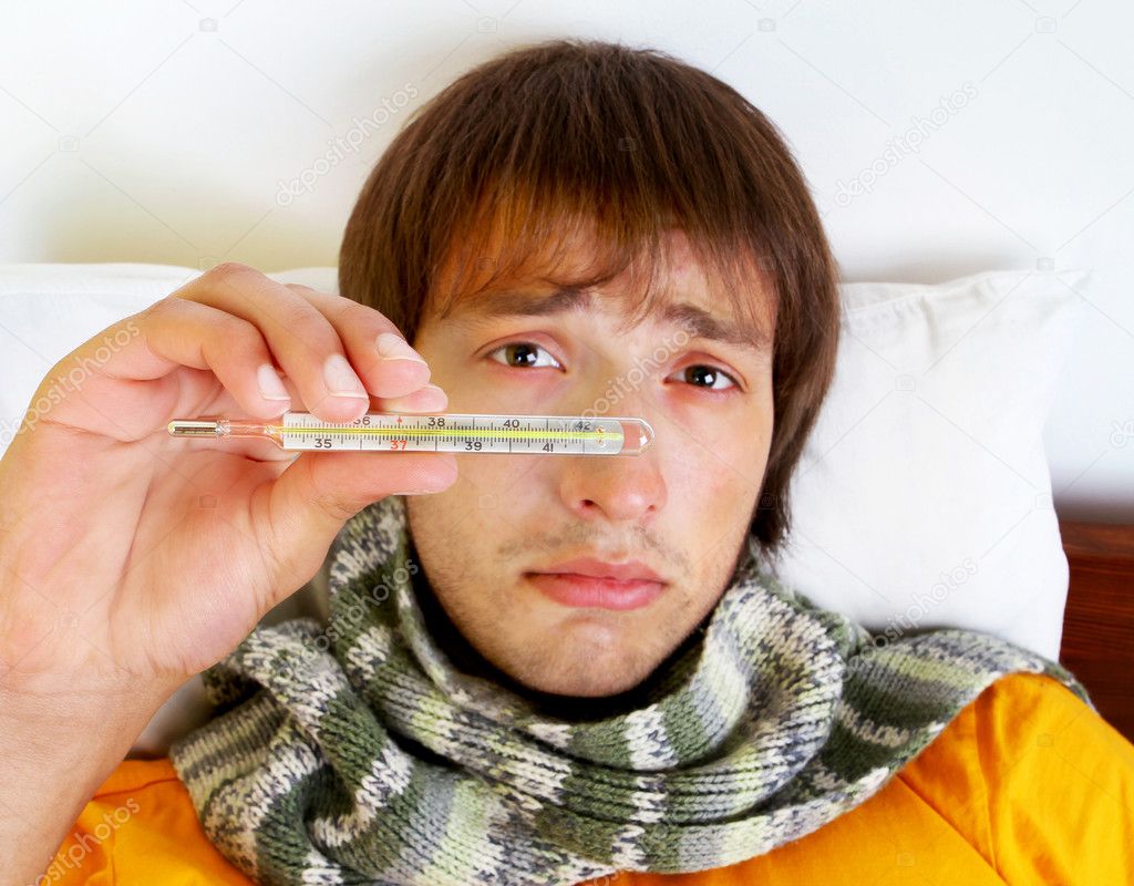 Young sick boy shows a thermometer with high temperature