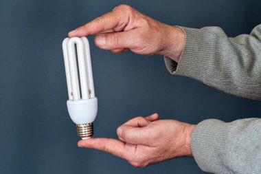 Energy saving bulb in hands clipart