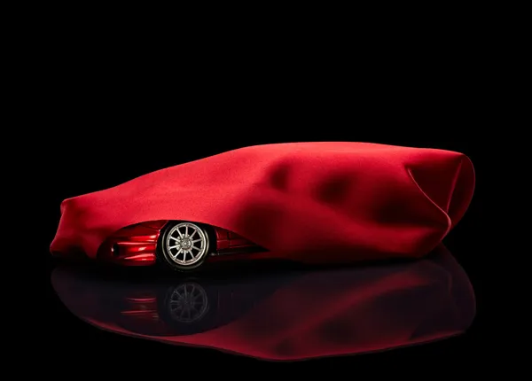 Nieuwe auto verborgen onder rode kaft — Stockfoto