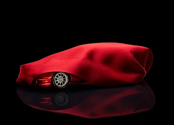 Novo carro escondido sob capa vermelha — Fotografia de Stock