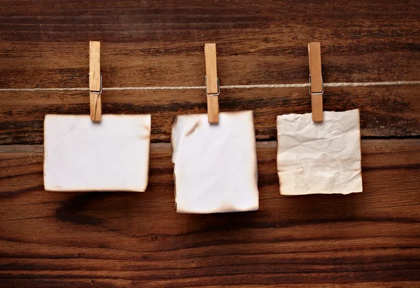Grunge-Notizpapier und Wäscheklammer auf Holz — Stockfoto