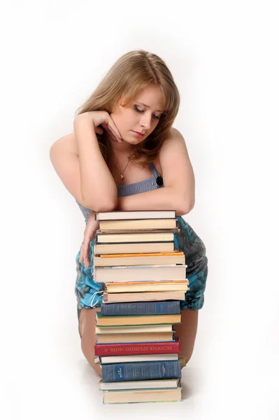 Chica estudiante encantadora sentada en una pila de libros — Foto de Stock