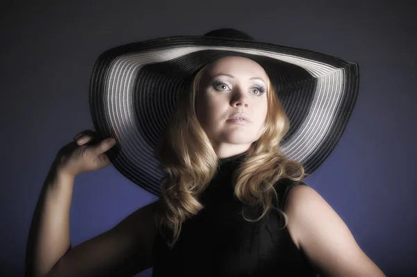 Fashion girl in a big hat in the studio — Stock Photo, Image