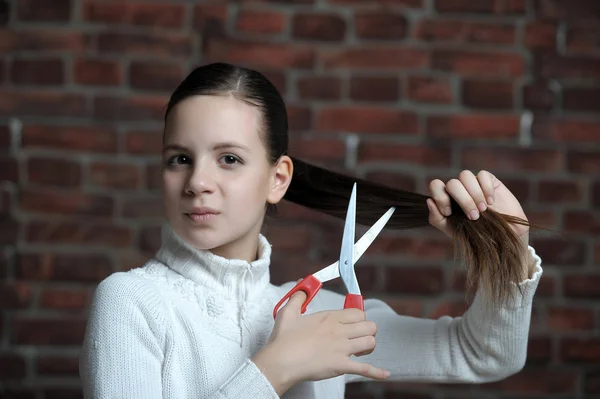 Het beeld van een meisje die haar haren snijdt — Stockfoto