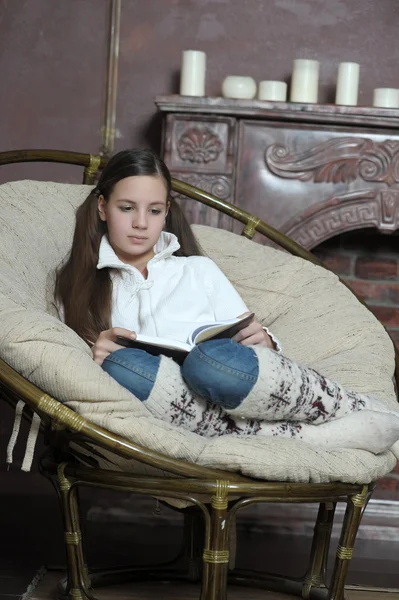Έφηβος κορίτσι διαβάζει ένα βιβλίο, ενώ κάθεται σε μια καρέκλα — Φωτογραφία Αρχείου