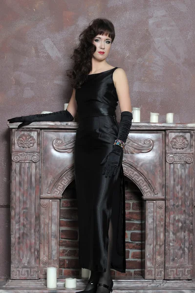Жінка в чорній сукні біля каміну — стокове фото