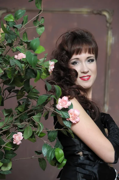 Mujer joven junto a un arbusto de rosas — Foto de Stock