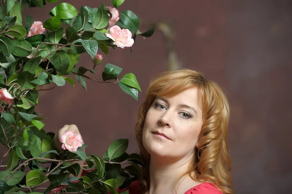 Young woman next to a bush of roses — Stock Photo, Image