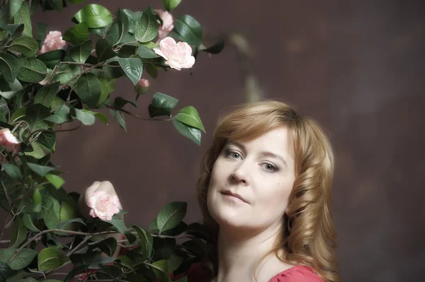 Jonge vrouw naast een struik van rozen — Stockfoto