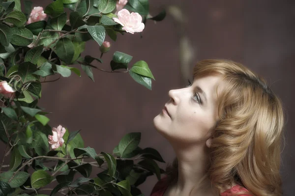 Jeune femme à côté d'un buisson de roses — Photo