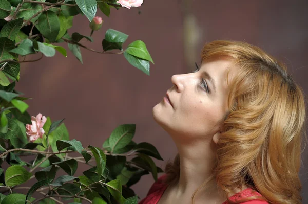 Young woman next to a bush of roses — Stock Photo, Image
