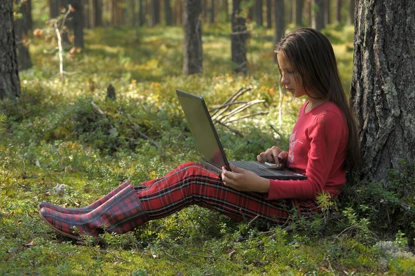 Menina bonita com um laptop está na floresta — Fotografia de Stock