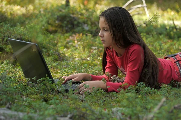 Beautiful girl with a laptop is in the woods — Stock Photo, Image