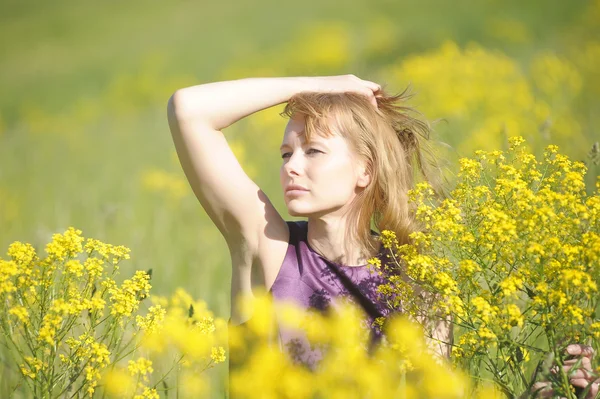 Flicka avkopplande i fält av blommor — Stockfoto