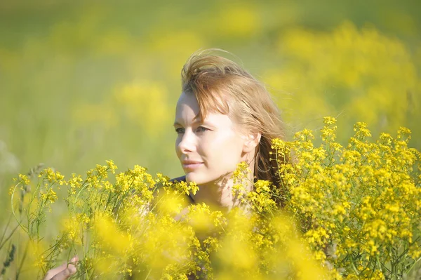 Flicka avkopplande i fält av blommor — Stockfoto