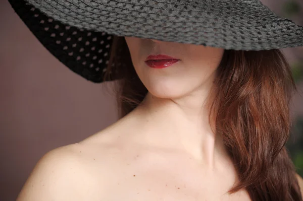 Kvinden med en bredskygget hat - Stock-foto