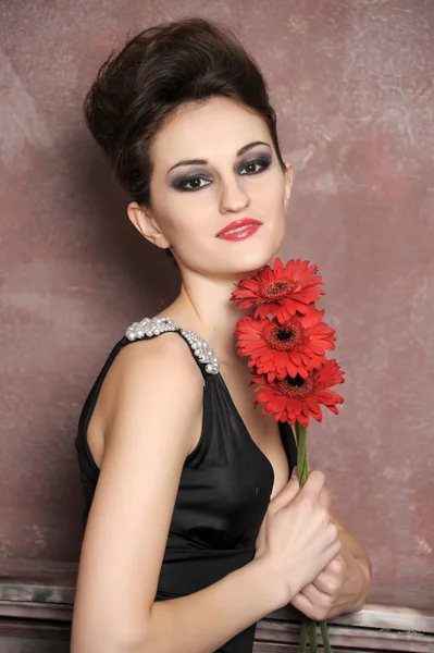Ελκυστική γυναίκα με κόκκινα λουλούδια — Φωτογραφία Αρχείου