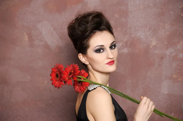 Aantrekkelijke vrouw met rode bloemen — Stockfoto