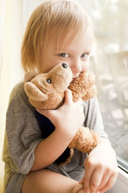 Small boy is seating near the window with toy clipart