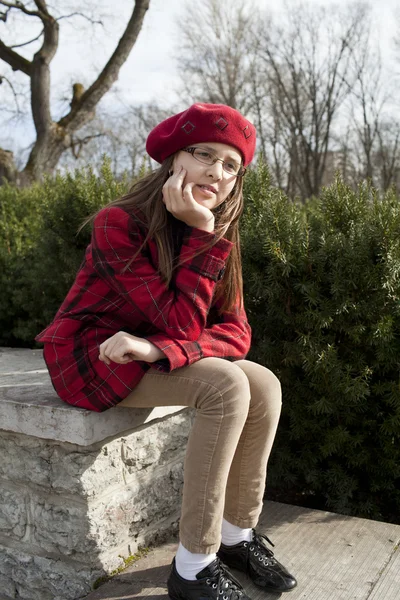 Positive schoold age girl is seating in the park — Stock Photo, Image