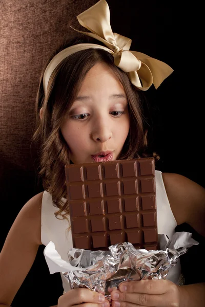 女孩与大巧克力和巧克力看一个头上的蝴蝶结 — 图库照片