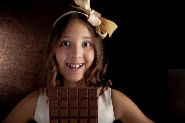 Girl with the big chocolate and with bow on a head looking at camera