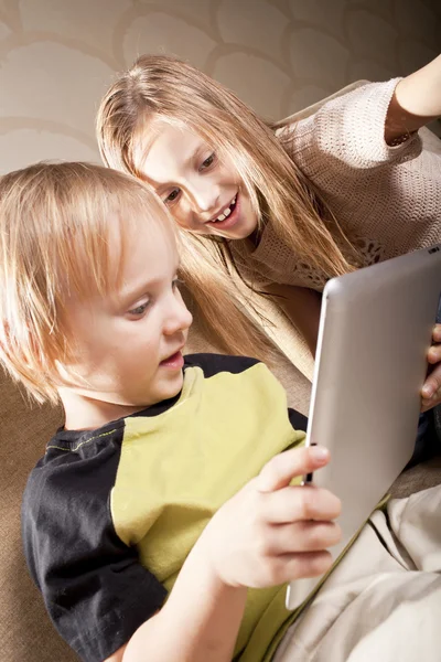 Улыбающаяся девочка и мальчик с планшетным компьютером — стоковое фото
